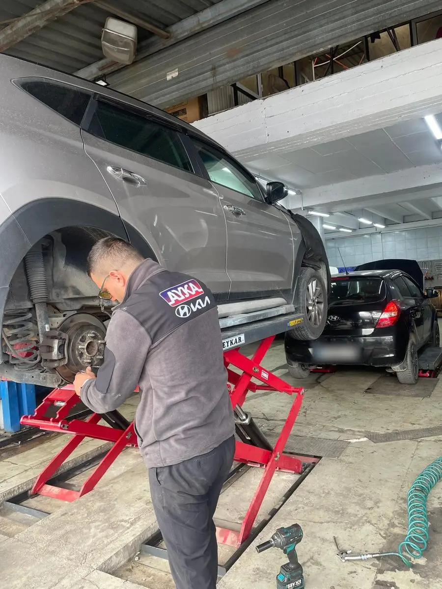 Lift üzerindeki SUV'un arka fren diski ve kaliperi üzerinde çalışan AYKA yelekli usta