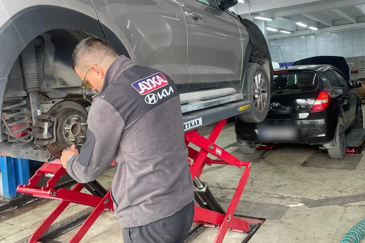 Lift üzerindeki SUV'un arka fren diski üzerinde çalışan Ayka Otomotiv ustası