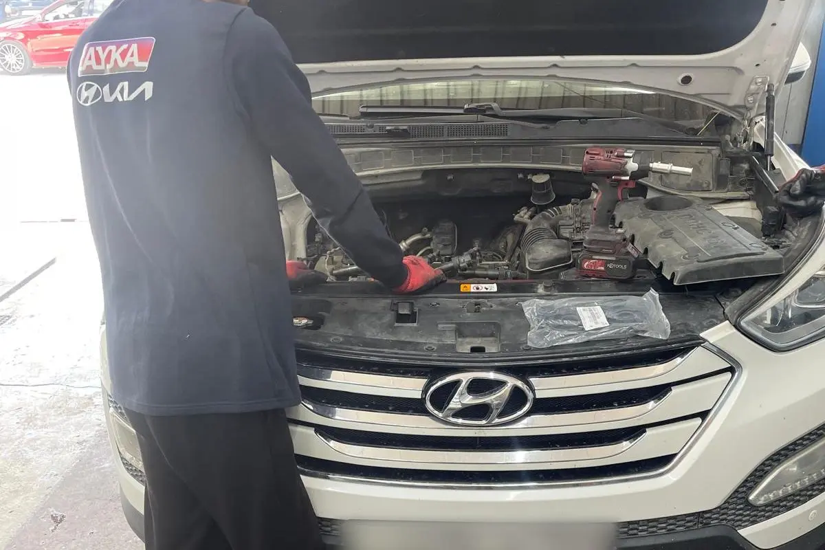 Kaputu açık Hyundai Santa Fe'nin motor bölmesinde çalışan Ayka Otomotiv ustası